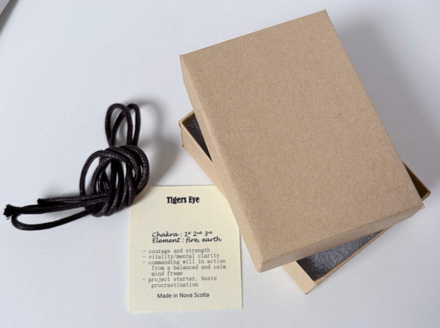 Dark brown cord to wear pendant, kraft colour jewelry box packaging, spiritual information card about tigers eye pendant on a white background