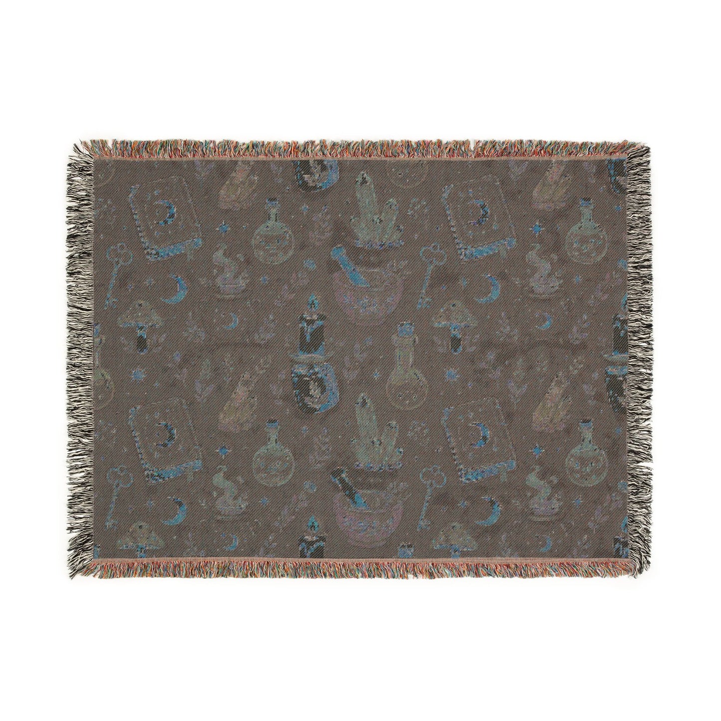 Back of Large sized witchy woven blanket shown flat, featuring a muted apothecary pattern with crystals, moons, potion bottles, spell books and fringed edges. 80"x60"