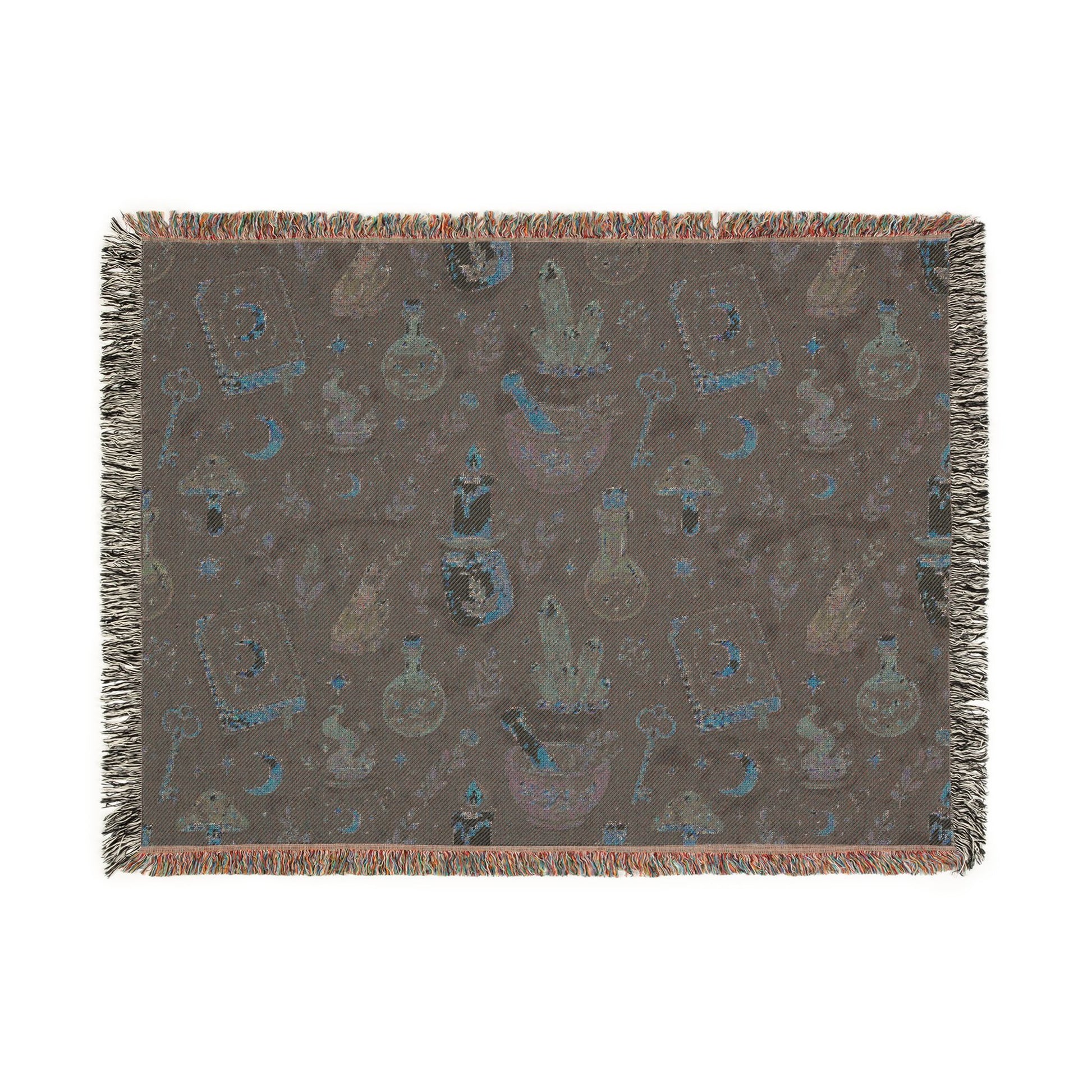 Back of Large sized witchy woven blanket shown flat, featuring a muted apothecary pattern with crystals, moons, potion bottles, spell books and fringed edges. 80"x60"