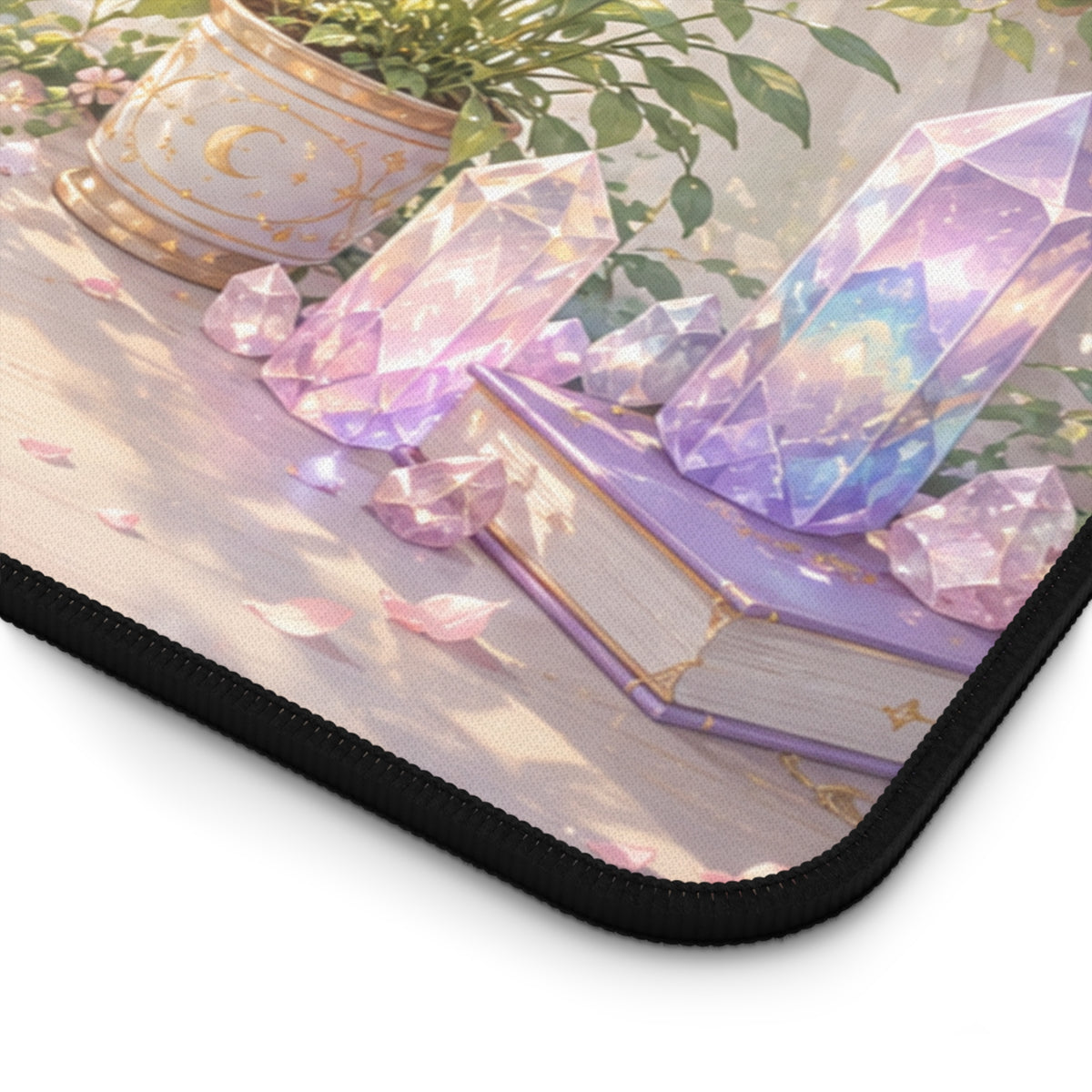 Corner - Close-up of a pastel cottagecore crystal desk mat with purple gemstones, floral details, a lavender book and black stitched border.