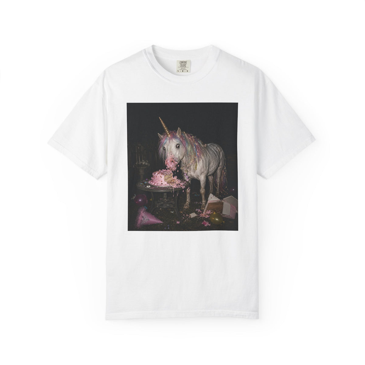 White graphic t-shirt with a retro-style photo of a unicorn stealing pink birthday cake at a dark party scene, shown on a white background.