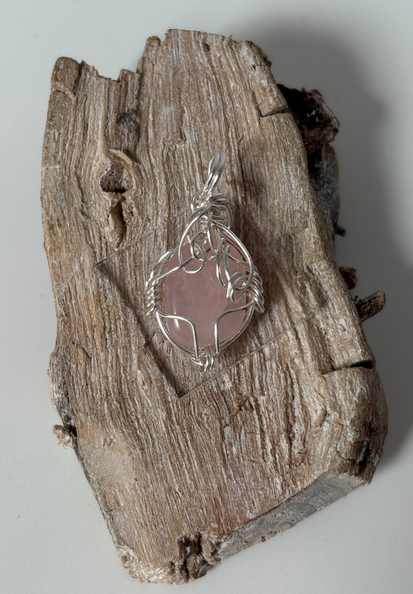 Silver pendant on a piece of wood with a plain background