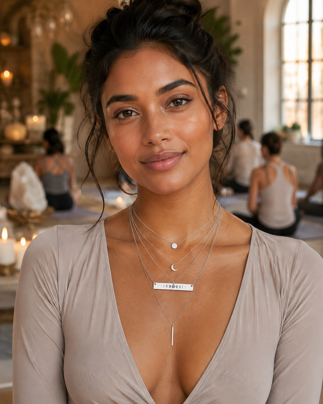 Woman wearing layered stainless steel necklaces in a restaurant setting. One necklace is a horizontal bar moon phases pendant.