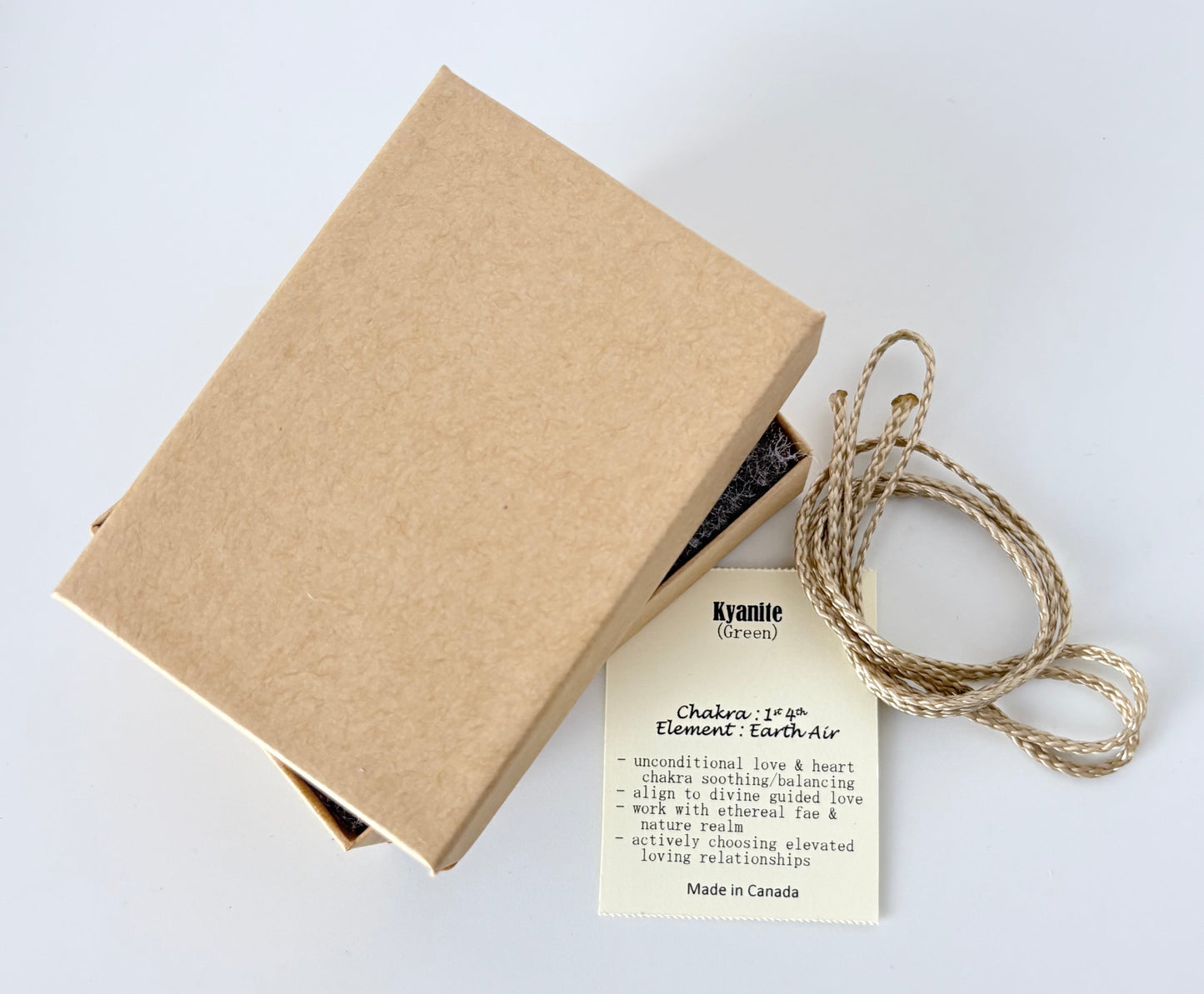 Kraft paper jewelry box with a green kyanite information tag and cream colour cord for a pendant on a white background