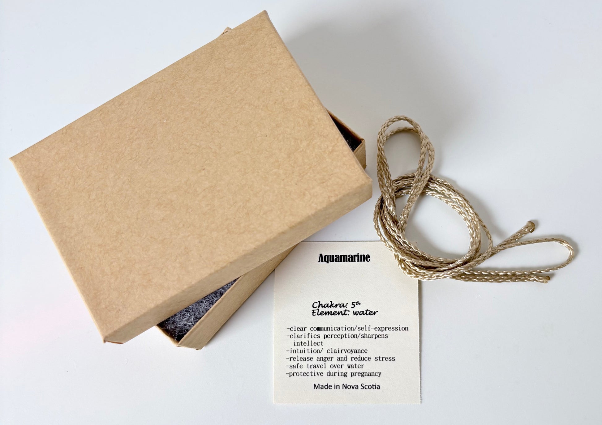 Kraft paper jewelry box with an aquamarine information tag and cream colour cord for a pendant on a white background