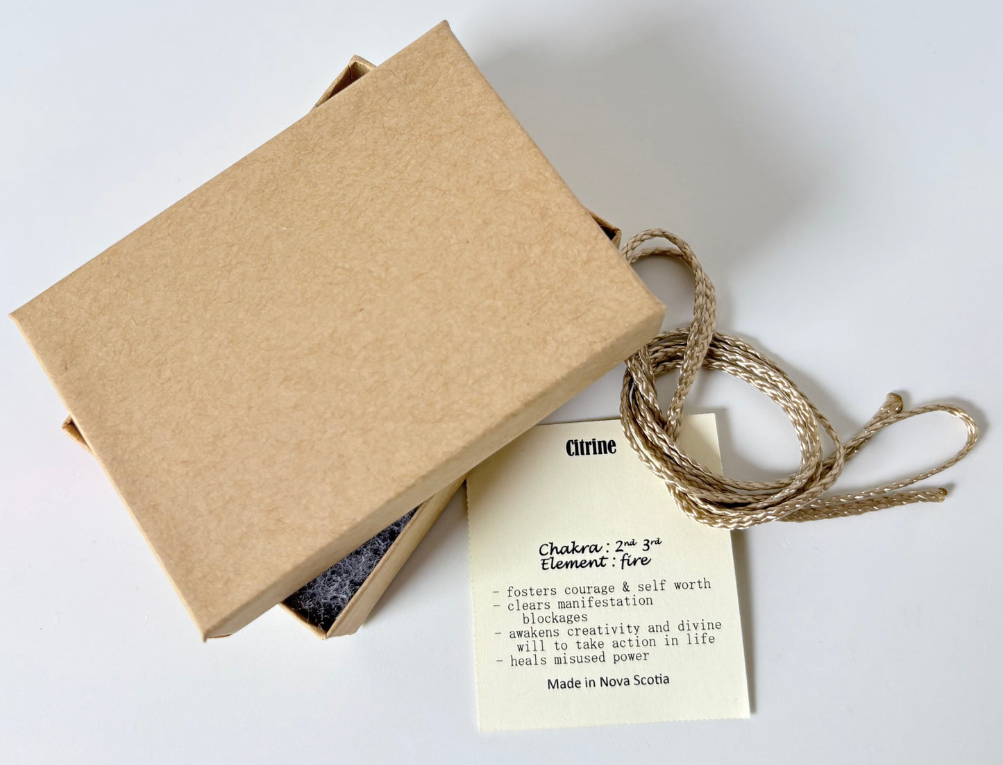 Kraft paper jewelry box with a citrine information tag and cream colour cord for a pendant on a white background