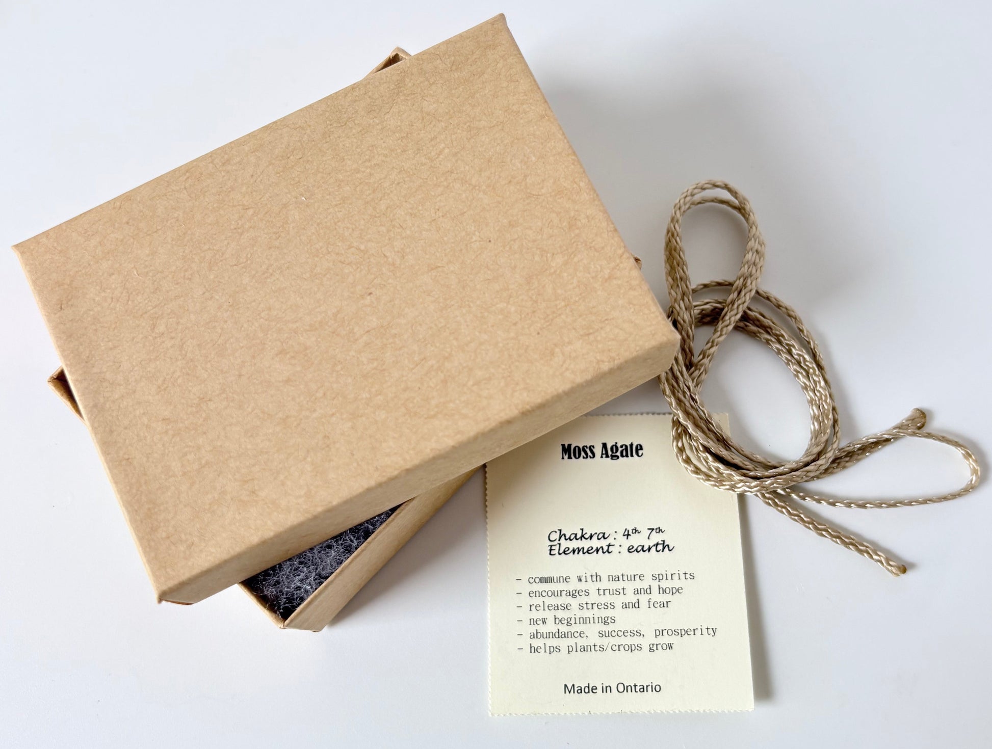 Kraft paper jewelry box with a moss agate information tag and cream colour cord for a pendant on a white background