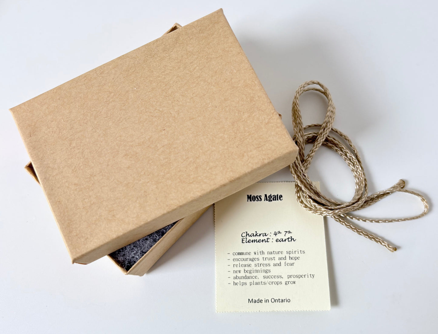 Kraft paper jewelry box with a moss agate information tag and cream colour cord for a pendant on a white background