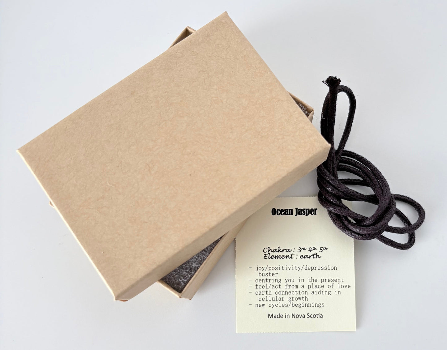 Kraft paper jewelry box with an ocean jasper information tag and cream colour cord for a pendant on a white 