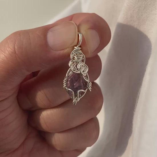 Lepidolite Pendant - Video of a wire-wrapped purple lepidolite stone pendant held between fingers over a white background, showing both front and back sides in natural lighting.