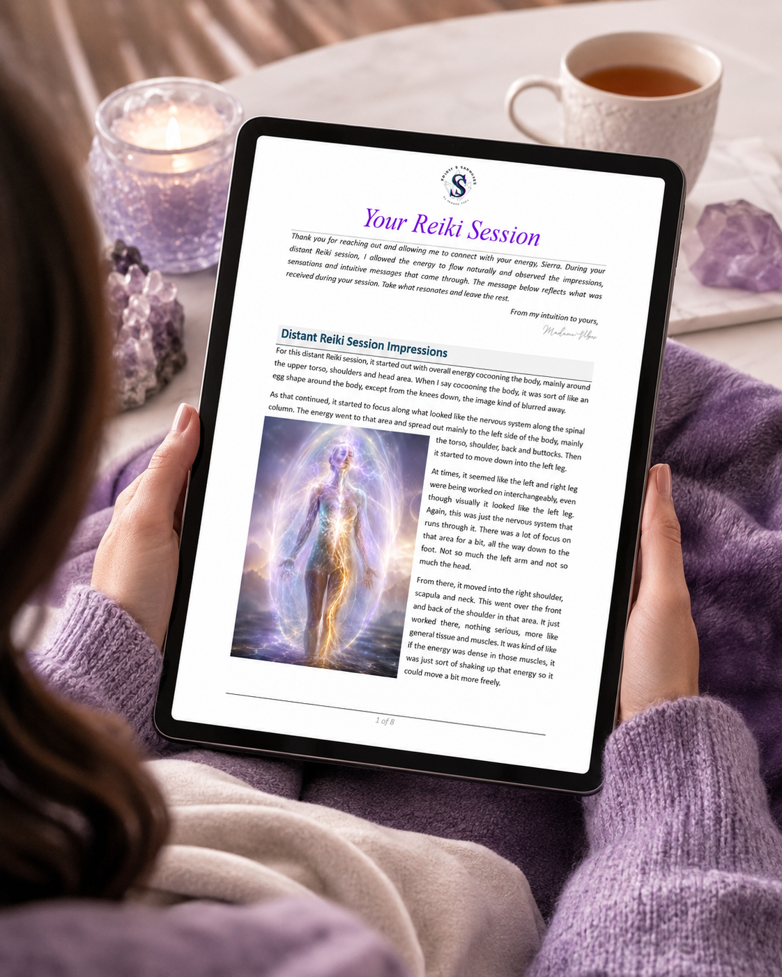 Person holding a tablet with Spirit and Sapphire distant Reiki session write up on a table with candles and crystals.